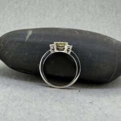 Anillo de oro blanco con diamante amarillo de laboratorio talla princesa y diamantes laterales blancos.
