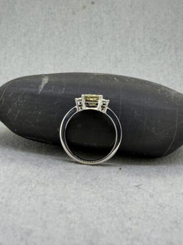 Anillo de oro blanco con diamante amarillo de laboratorio talla princesa y diamantes laterales blancos.