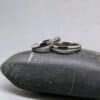 Pareja de alianzas de boda de 3.5 mm de ancho con perfil de media caña suave; se muestran los dos anillos sobre fondo neutro en perspectiva, destacando la base de titanio gris brillante pulido, la línea fina central de carbono negro y los cinco diamantes brillantes en la alianza de mujer.