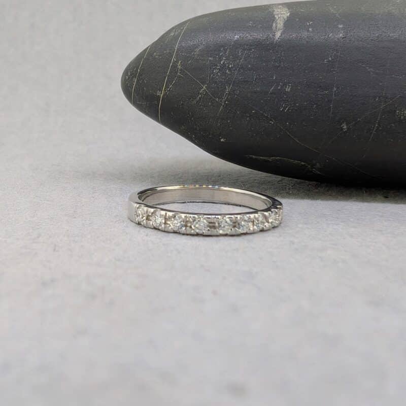 Vista lateral de anillo tipo media alianza de oro blanco mostrando el espesor del brazo y la colocación de los diamantes.