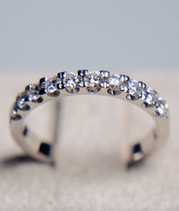 Primer plano macro de una media alianza de oro blanco de 18k mostrando el detalle de los diamantes naturales de 0.50 cts en total, resaltando la simetría del engaste y el brillo de las piedras.